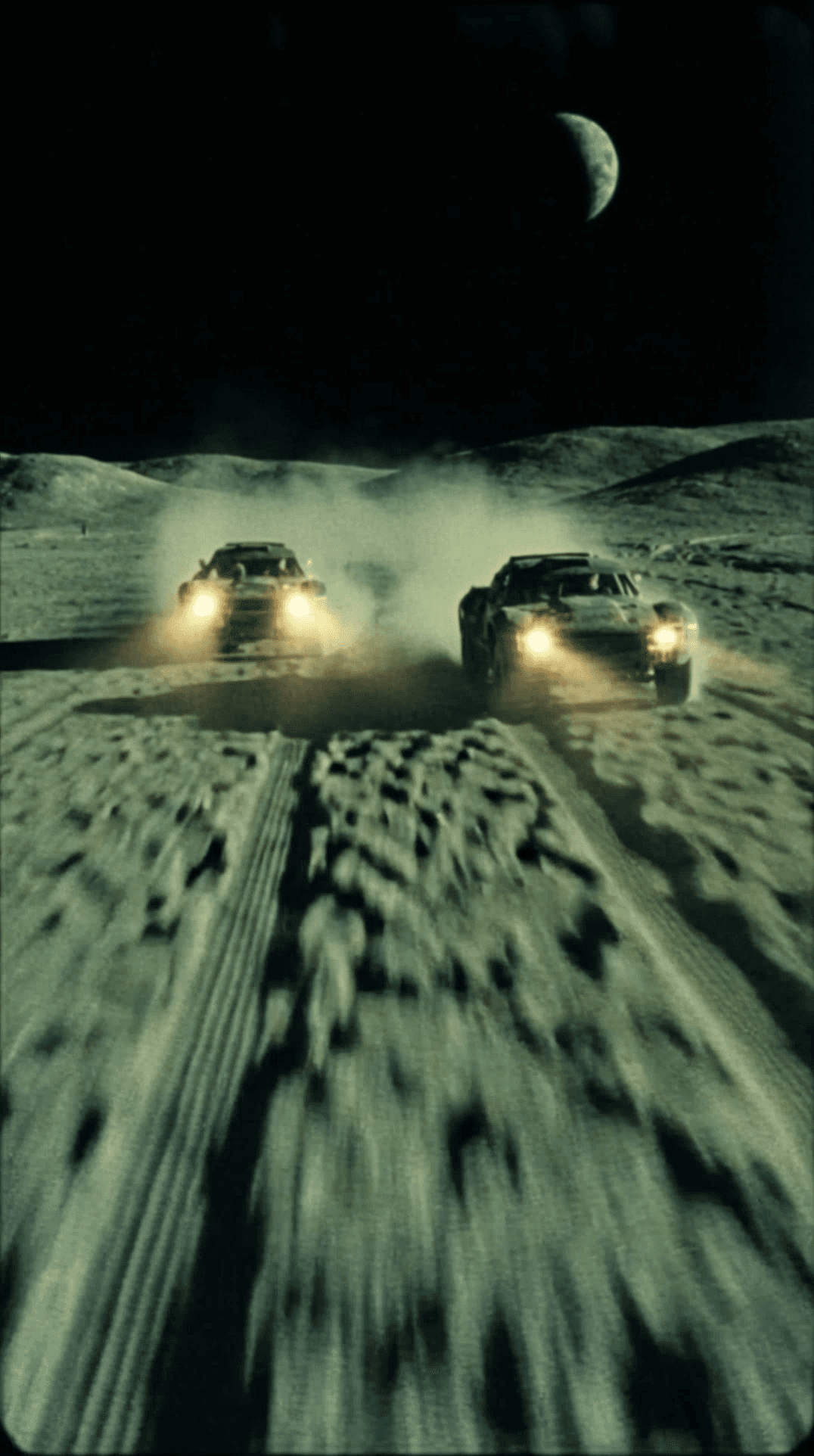 Low POV. Two race cars ahead on a barren alien surface, offset slightly left and right. Deep tire tracks carve through the terrain, leading the eye forward. Bottom of frame partially blocked by dark vehicle silhouette. ENVIRONMENT Desolate moon-like landscape, dusty granular ground, no vegetation, no structures. Rolling terrain stretches to the horizon. A massive planet or moon hangs low in the sky, partially shadowed, softly glowing. ACTION Cars racing forward at speed, dust trails illuminated by headlights. Ground texture streaks from motion. No explosions, no spectacle — pure mechanical movement. LIGHTING Only practical light from vehicle headlights. Harsh beams cut across the ground, creating long shadows and blown highlights. Sky remains almost pitch black. CAMERA / OPTICS Analog 16mm / degraded 35mm look. Heavy film grain, noise crawling in shadows, slight motion blur. Imperfect focus. No modern sharpness. Slight exposure flicker. COLOR / GRADE Muted toxic palette: dirty greens, pale cyan highlights, sickly moonlight, deep blacks. Looks chemically processed, underexposed, imperfect color correction. STYLE Bootleg sci-fi realism. Feels like forbidden footage from a lost 70s experimental film. Documentary, procedural, cold, lonely. No polish. NEGATIVE / DO NOT No neon, no futuristic UI, no clean CGI, no epic glow, no text, no logos, no people visible, no stylization. OUTPUT Raw analog sci-fi racing footage, grounded, eerie, cinematic realism.